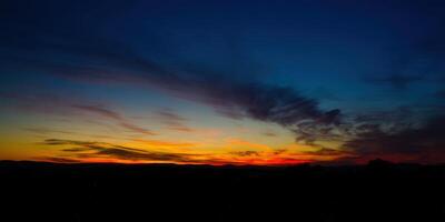 The sky explodes in color during a beautiful sunset over the tranquil horizon. photo