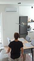 Man using remote control to adjust air conditioner in bright modern living room. Person adjusting temperature for cooling during hot summer days. Concept of home comfort video