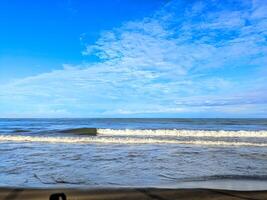 Serene Coastal Seascape Gentle Waves Under a Vast Blue Sky with Wispy Clouds. photo
