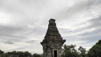 Ancient Indonesian Temple Tower Against a Cloudy Sky photo