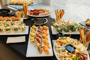 Well-arranged catering table with gourmet appetizers, finger foods, vegetables, cold cuts, and dips served for a special event. photo