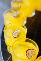 Refreshing yellow cocktails with passion fruit garnish served in glasses, ideal for summer parties, events, or tropical-themed celebrations. photo