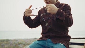 Man Holding A Rosary In His Hands During A Prayer On The Beach video
