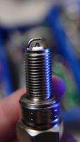 4K-resolution close-up of a metallic spark plug against a blurred workshop background, showcasing fine details. video