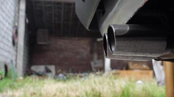 Close-up detail of a car muffler during engine startup, capturing subtle vibrations and initial exhaust emissions video