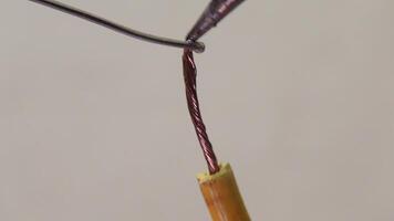 Close-up of soldering a stripped copper cable, showcasing the use of precise tools for electrical work, emphasizing craftsmanship and technical skills. video