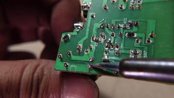 Removing electronic components using a soldering iron, demonstrating a circuit board repair process. video