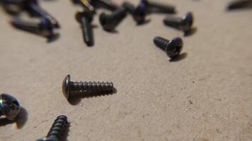 Slow motion shot of metal bolts falling onto a table. Bolts and screws on a wooden work bench. video