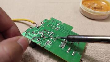 A detailed image showcasing the process of soldering components on a green circuit board. video