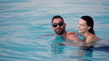 Cheerful couple spending time in the pool, smiling and enjoying their holiday. Concept travel, leisure and romance video