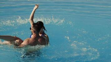 Very happy couple in sunglasses enjoying each other in a swimming pool, man holding woman in his arms, both smiling and relaxed. Concept vacation, travel, relaxation video