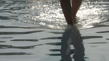 An unrecognizable woman walking on water in the pool on a hot sunny day. Concept summer relaxation, warmth. video
