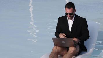 Man in suit using laptop by pool video