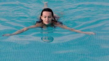 Concept summer relaxation, beauty and calm. Beautiful young woman enjoying a sunny day while lounging in a pool. video