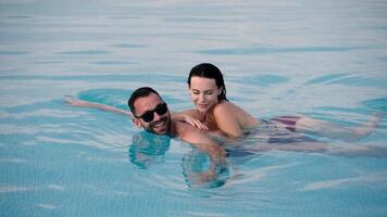 Young man and woman spending a joyful moment in a pool under the open sky. Concept happiness, vacation and connection. video