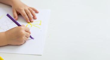 Child's Hand Drawing with Purple Marker on White Paper, Close-Up View, Creative Process. photo