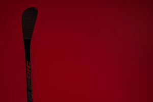 Close-up of a Hockey Stick Blade Against a Red Background. The image showcases the detailed texture and design of the hockey stick blade. photo