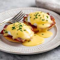 Delicious Eggs Benedict with Rich Hollandaise Sauce on a White Plate. photo