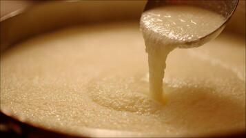 Creamy liquid pouring from a ladle into a pot. photo