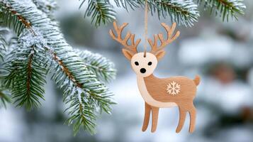 Wooden christmas reindeer ornament hanging on a snowy pine tree branch photo