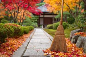 Broom sweeping fallen autumn leaves in japanese garden photo