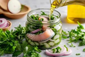 Chef pouring olive oil into jar with marinated salmon, cucumber, onion, and parsley photo