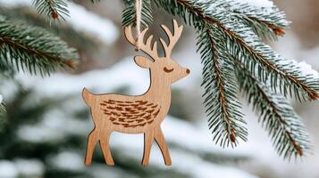 Wooden christmas reindeer ornament hanging on a snowy pine tree branch. . photo
