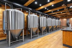 Modern craft brewery showing stainless steel conical fermenters in a row photo