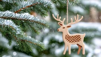 Wooden christmas reindeer ornament hanging from snowy pine tree branch photo