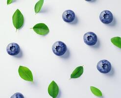 Fresh blueberries and leaves on a white surface photo