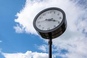 Vintage-style Clock Stands Tall Against a Bright Blue Sky With Fluffy White Clouds During a Sunny Afternoon photo