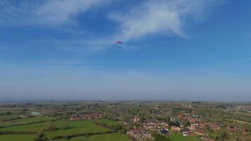 Aerial drone view of paraglider drifting over lush spring fields in England sunshine video