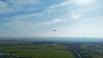Sunny spring aerial drone footage of paraglider gliding over English hills and fields video