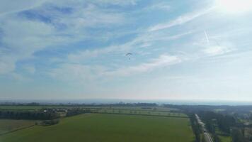 English countryside paraglider flying captured by drone on clear sunny spring day video