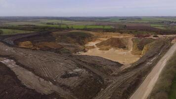 Drone flyover of open cast quarry with earthmoving equipment England video