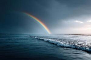 Dramatic sky with vivid rainbow arching above ocean waves at dusk photo