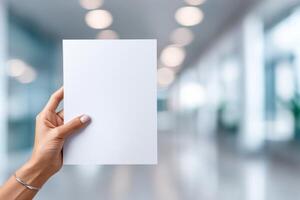 Displaying a blank paper sheet in hands within a bright and welcoming office environment photo