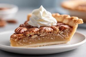 Delicious slice of pecan pie topped with whipped cream and pecan halves on a white plate photo