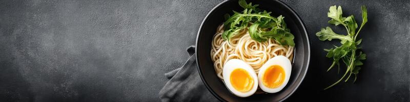 Hearty bowl of ramen with soft-boiled eggs and fresh greens served on textured surface photo