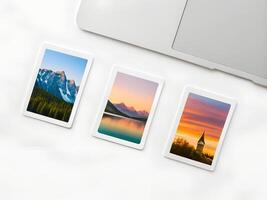 Three Landscape Photographs on a White Surface Near a Laptop photo