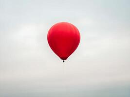 Red Hot Air Balloon Ascending in a Cloudy Sky photo