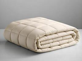 Cream Colored Quilted Blanket Folded on a White Surface photo