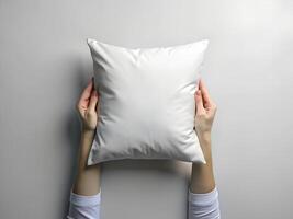 a person holding a white pillow on a gray background photo