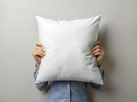 Person Hiding Face Behind Large White Pillow Against Gray Background photo