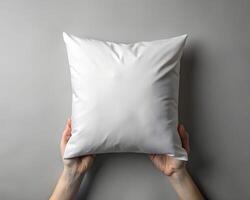 Overhead Shot of Hands Holding a Blank White Square Pillow Against a Grey Background photo