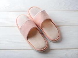 Peach Colored Terry Cloth Slippers on White Wooden Background photo