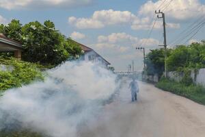 A man walking down a street with a large cloud of smoke coming from a building photo