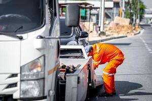 A man in an orange uniform is fixing a flat tire photo