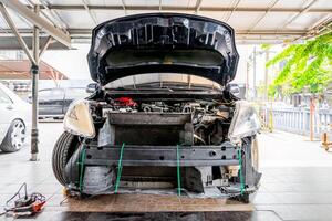 A car with its hood open and the engine on the ground photo