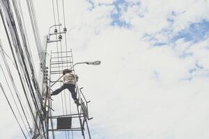 A man climbing up a ladder on a power line photo